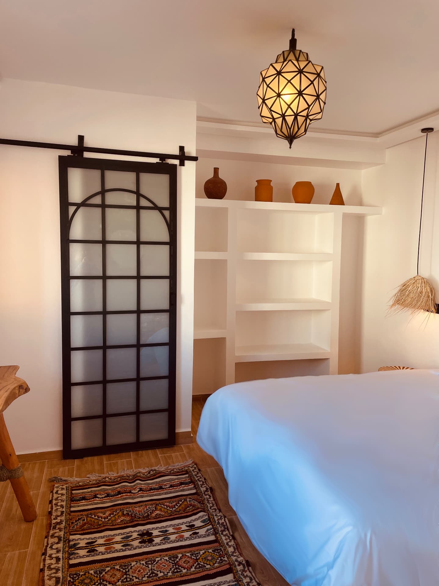 Porte coulissante en métal noir et verre dépoli, lanterne marocaine allumée