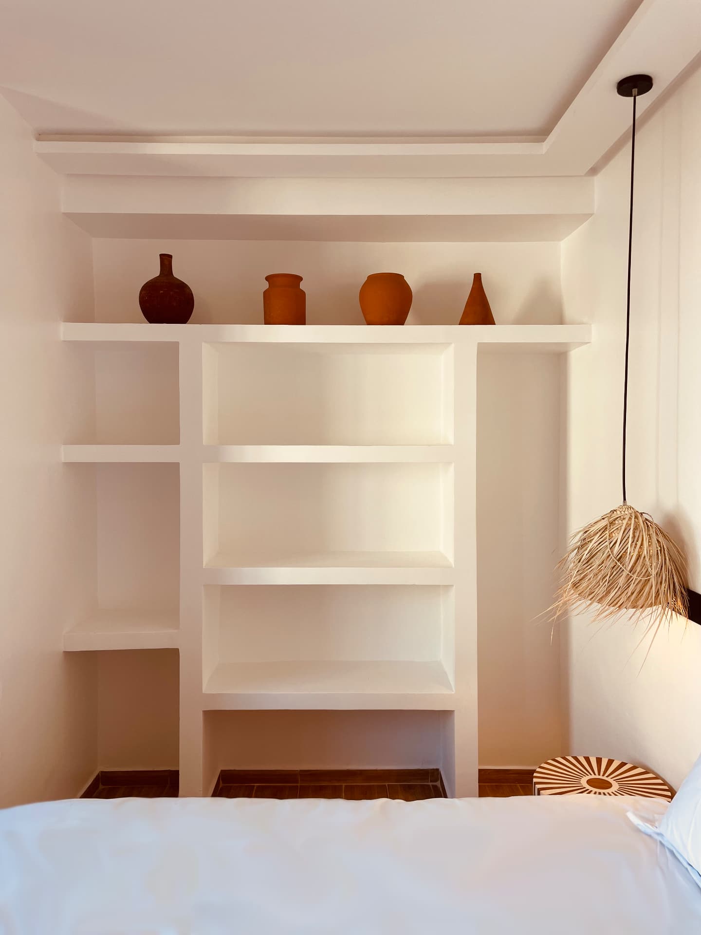 Niches blanches en plâtre avec poteries en terre cuite au-dessus du lit